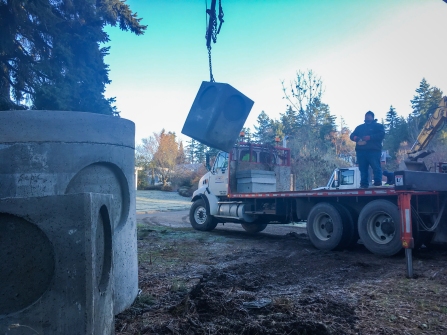 A concrete stormwater vault is lifted off the delivery truck